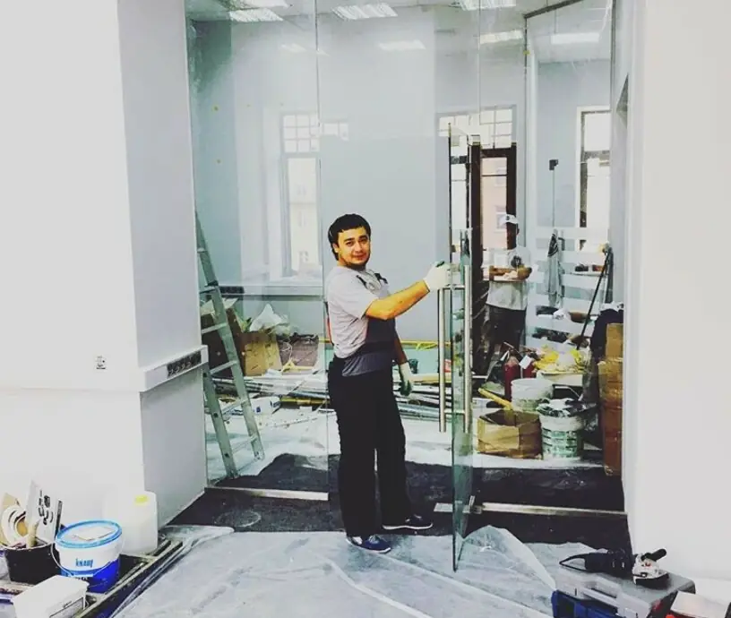 Монтажник ставит стеклянную дверь